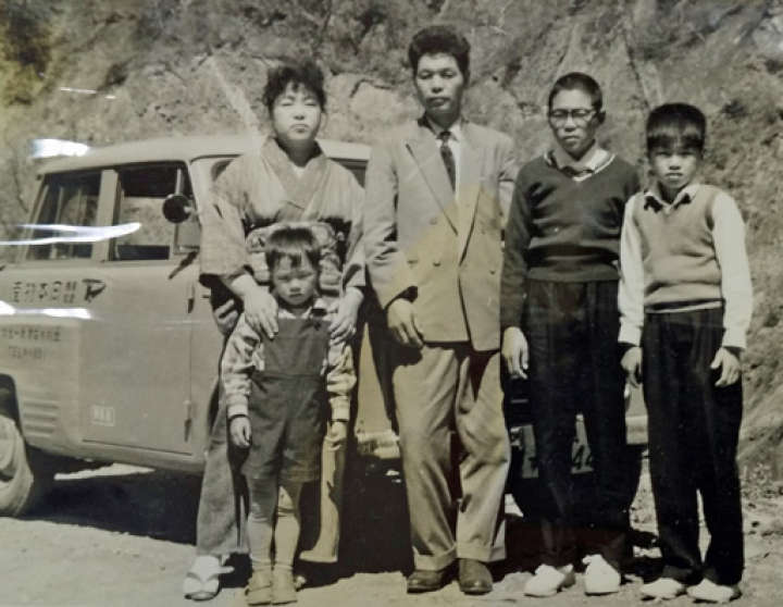 ダットサンの前で家族と記念写真に納まる岡本さん（右から2人目）