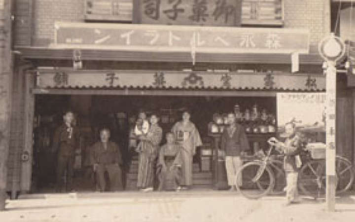 １９３０年に店舗前で写真に収まる原田一家。真ん中でだっこされているのが俊一さん