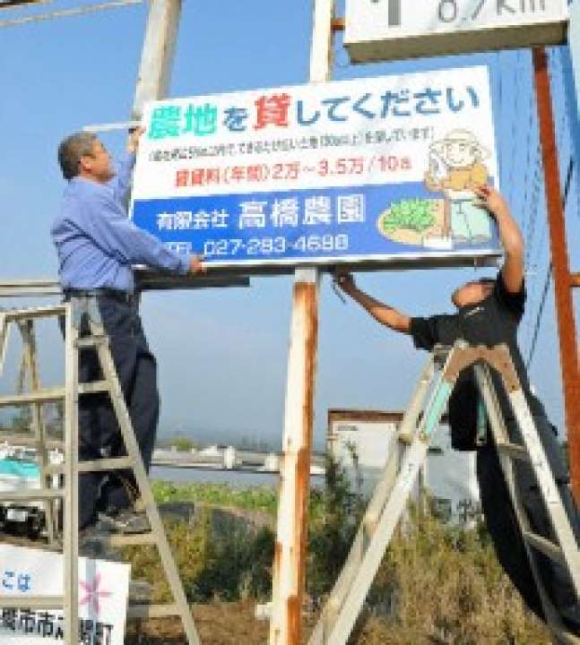 「農地を任せて」と社長の高橋喜久男（左）。専務の潤（右）と農地募集の看板を設置した＝11月、前橋市
