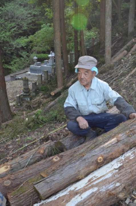 ことし４月、地区住民の依頼で墓を覆うように茂っていたクリの木を伐採した市川辰治さん。「明るくなって良かった」と話す